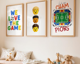 May include: Three framed wall art prints featuring building block themes. The first reads WE LOVE THE GAME with a soccer ball. The second shows three minifigure heads. The third displays a soccer stadium with the text We are CHAMPIONS.