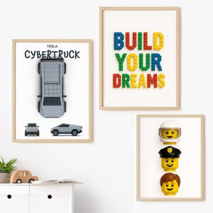 May include: Three framed prints with a light wood frame. One print features a gray Tesla Cybertruck with the text "Tesla Cybertruck". Another print says "Build Your Dreams" in colorful block letters. The third print shows three Lego heads.
