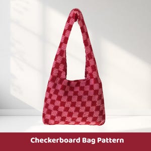 May include: A handmade, crochet shoulder bag in a red and pink checkerboard pattern. The bag has a long strap and a spacious interior. The text "Checkerboard Bag Pattern" is displayed at the bottom of the image.