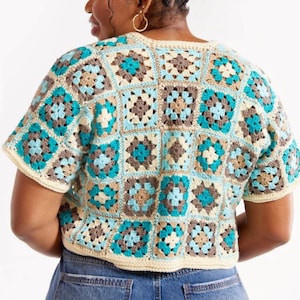 May include: A short-sleeved crochet top in a granny square pattern. The top features squares in shades of teal, brown, beige, and cream. The garment is visible from the back and is paired with blue denim jeans.