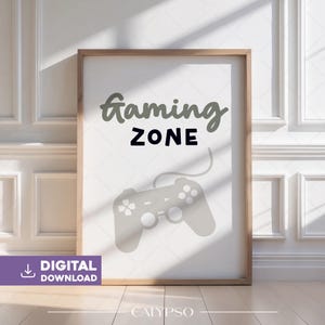 May include: A framed print with the words "Gaming ZONE" in a playful font, accompanied by a gray game controller graphic. The print has a light wood frame and a white background. The words "DIGITAL DOWNLOAD" are in a purple box in the lower left corner.