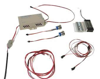 Puede incluir: Un conjunto de componentes de sistema de seguridad que incluye una unidad de control de alimentación, dos botones de liberación de puerta, una cerradura de puerta magnética y cableado. La unidad de alimentación está etiquetada como "Power Supply Control".