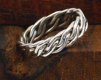 Op de afbeelding: Een zilveren gevlochten ring met een gladde, gepolijste afwerking. De ring is gemaakt van een dikke, gevlochten band.
