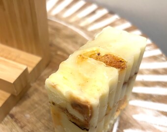 May include: A bar of handmade soap with layers of white and brown. The soap is on a wooden surface.