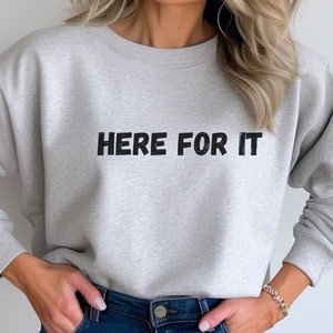 May include: A gray sweatshirt with the text "HERE FOR IT" printed in black.