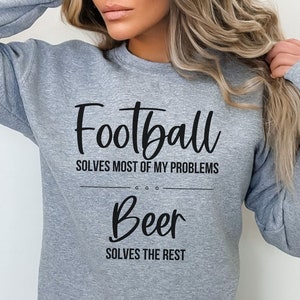 May include: A gray sweatshirt with the text "Football solves most of my problems... Beer solves the rest" printed in black.