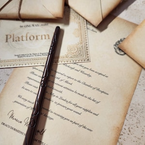 May include: A brown wooden wand with intricate carvings. The wand is lying on a piece of parchment paper with text that reads "Witchcraft and Wizardry" and "You that you been accepted at".