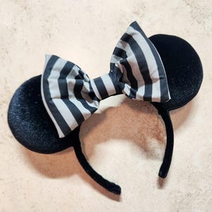 May include: Black velvet mouse ears headband with a black and white striped bow.