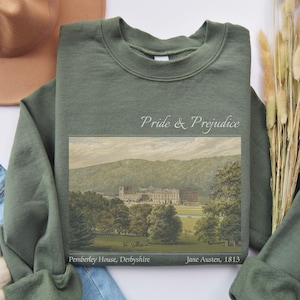 Puede incluir: Una sudadera verde con una ilustración vintage de Pemberley House de Orgullo y Prejuicio de Jane Austen. El texto "Pride & Prejudice", "Pemberley House, Derbyshire" y "Jane Austen, 1813" está impreso en la sudadera.