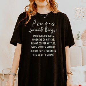 Puede incluir: Camiseta negra con texto blanco que dice "A few of my favourite Things:" seguido de una lista de elementos: "Raindrops on roses. Whiskers on kittens. Bright copper kettles. Warm woolen mittens. Brown paper packages tied up with string."
