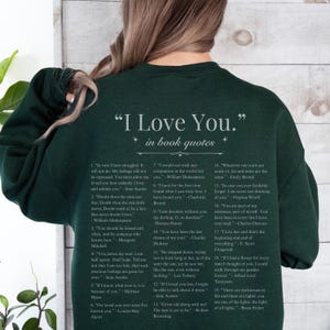 Op de afbeelding: Donkergroene sweatshirt met de tekst "I Love You" en citaten uit boeken. De sweatshirt heeft een lijst met citaten over liefde van verschillende auteurs, waaronder Jane Austen en William Shakespeare.