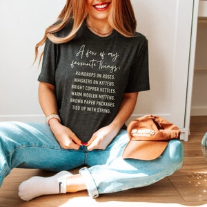 Puede incluir: Una camiseta gris oscuro con texto blanco que dice "A few of my favorite things: Raindrops on roses. Whiskers on kittens. Bright copper kettles. Warm woolen mittens. Brown paper packages tied up with string."