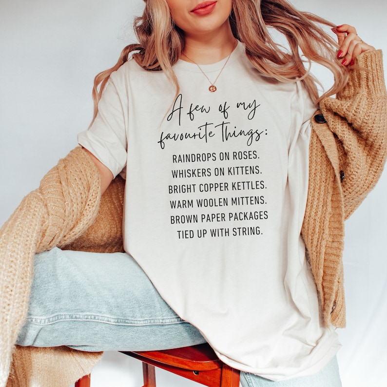 Puede incluir: Una camiseta blanca con texto negro que dice "A few of my favourite Things:" seguido de una lista de elementos: "Raindrops on roses, Whiskers on kittens, Bright copper kettles, Warm woolen mittens, Brown paper packages tied up with string."