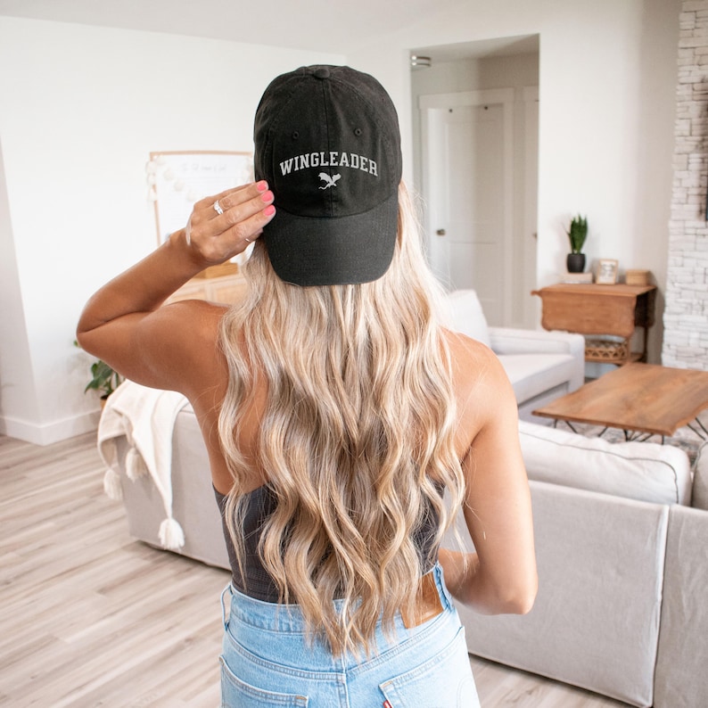 May include: A black baseball cap with the text "WINGLEADER" embroidered in white on the front. The cap has a curved brim and a white bird design.