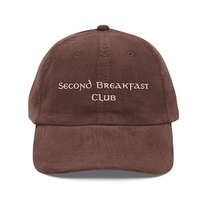 Könnte beinhalten: Eine braune Baseballkappe aus Cord mit weißer Stickerei, auf der "Second Breakfast Club" steht.