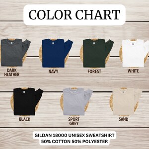 K&ouml;nnte beinhalten: Farbkarte mit verschiedenen Farben von Gildan 18000 Unisex-Sweatshirts. Die Farben sind: Dunkelgrau meliert, Marine, Wald, Wei&szlig;, Schwarz, Sportgrau und Sand. Der Text "Gildan 18000 Unisex-Sweatshirt 50% Baumwolle 50% Polyester" befindet sich am unteren Rand des Bildes.
