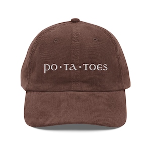 May include: A brown corduroy baseball cap with white embroidered text that reads "po.ta.toes".