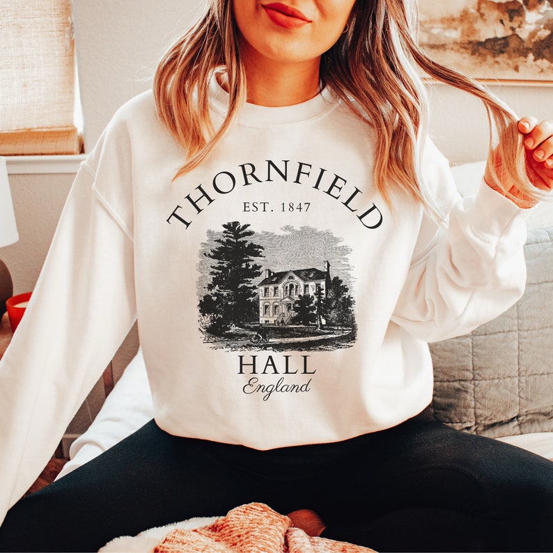 May include: White sweatshirt with a black graphic print of a house with the text "Thornfield Hall, Est. 1847, England"