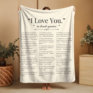 Könnte beinhalten: Eine weiße Kuscheldecke mit einem schwarzen und grauen Druck von Buchzitaten über die Liebe. Die Decke zeigt den Text "I Love You." in großen schwarzen Buchstaben oben. Die Zitate sind von 1 bis 19 nummeriert und beinhalten Autoren wie Jane Austen, William Shakespeare und F. Scott Fitzgerald.