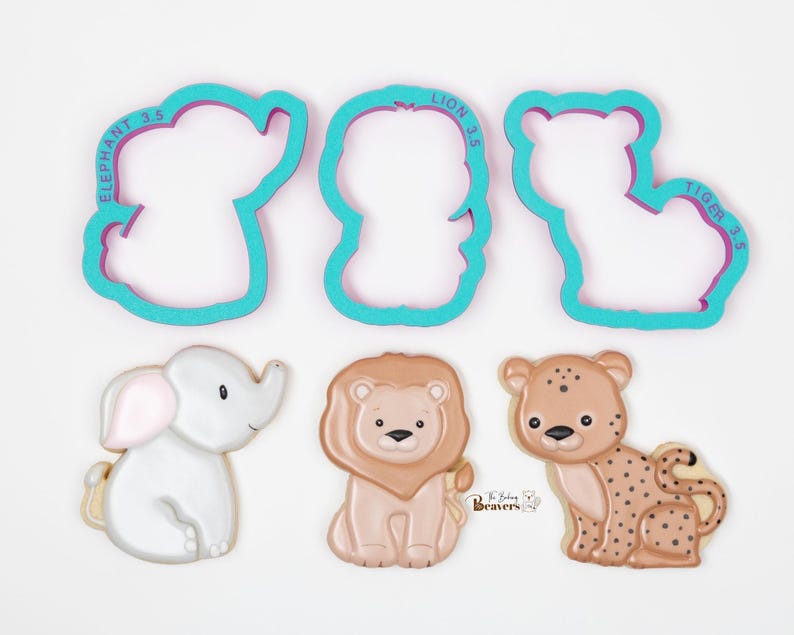 Puede incluir: Un juego de cuatro cortadores de galletas, con un elefante, un le&oacute;n, un tigre y un conjunto de tres galletas de animales. Los cortadores de galletas son de color azul turquesa con letras moradas. Las galletas est&aacute;n decoradas con glaseado y presentan un elefante, un le&oacute;n y un leopardo.