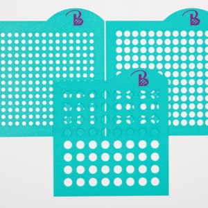 May include: Three turquoise blue stencils with circular cutouts of varying sizes. The stencils are made of a flexible material and are designed for crafting projects.