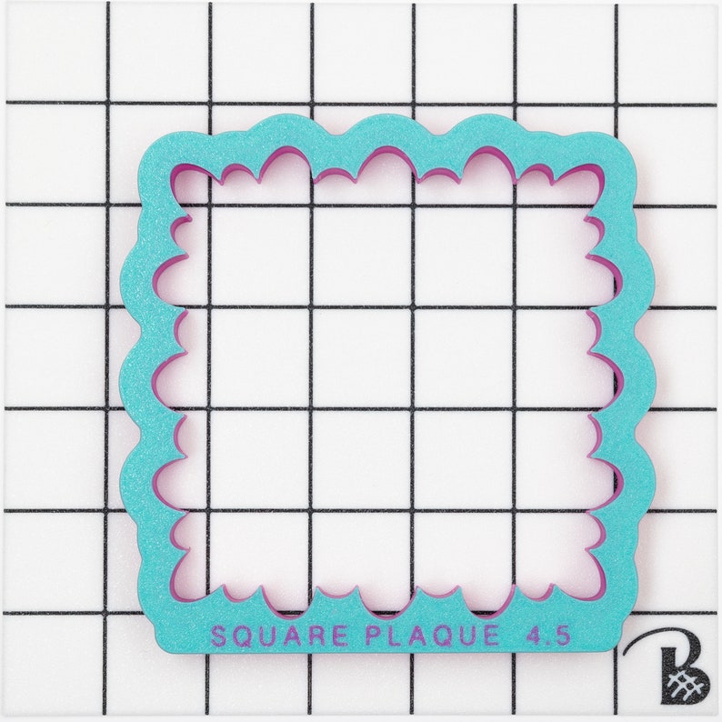May include: A turquoise blue square cookie cutter with a scalloped edge and the text "SQUARE PLAQUE 4.5" in pink.
