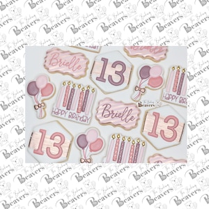 K&ouml;nnte beinhalten: Ein Set dekorierter Zuckerkekse mit rosa, wei&szlig;er und goldener Glasur. Die Kekse zeigen den Namen "Brielle", die Zahl "13" und den Spruch "Happy Birthday".