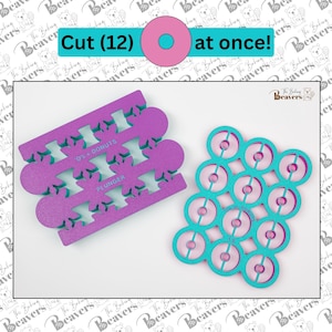 May include: A set of two purple and turquoise plastic donut cutters. The larger cutter has 12 donut shapes and the smaller cutter has three rows of four donut shapes. The text "O'z Donuts" and "Plunger" are printed on the smaller cutter.