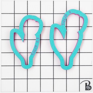 Op de afbeelding: Twee tulpenvormige koekjesvormen in turquoise blauw. De grotere vorm heeft de tekst "TULIP 4" erop gedrukt. De kleinere vorm heeft de tekst "TULIP 3.5" erop gedrukt.