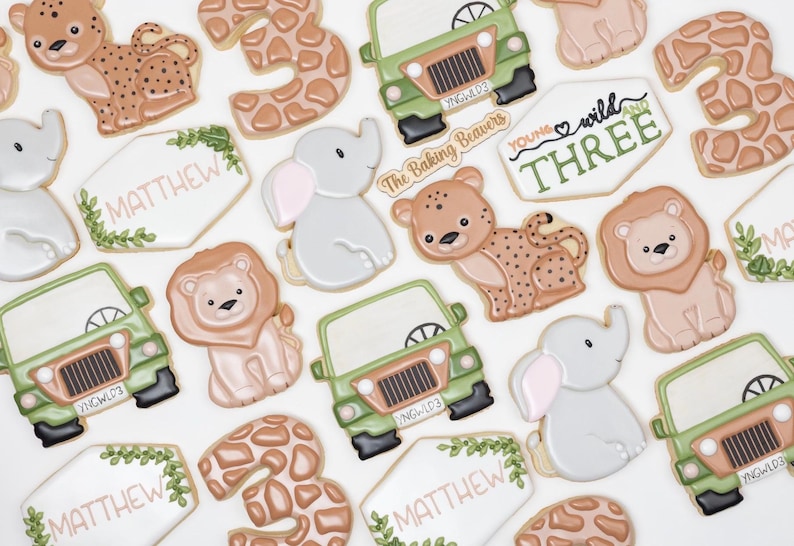 Puede incluir: Un conjunto de galletas de az&uacute;car decoradas con un tema de selva. Las galletas est&aacute;n decoradas con varios animales, incluyendo un le&oacute;n, un elefante, una jirafa y un leopardo. Las galletas tambi&eacute;n presentan los n&uacute;meros 3 y las palabras "You're Wild Three" y "Matthew".
