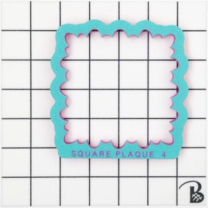 May include: A turquoise blue square cookie cutter with a scalloped edge and a pink inner edge. The cutter is labelled "SQUARE PLAQUE 4".