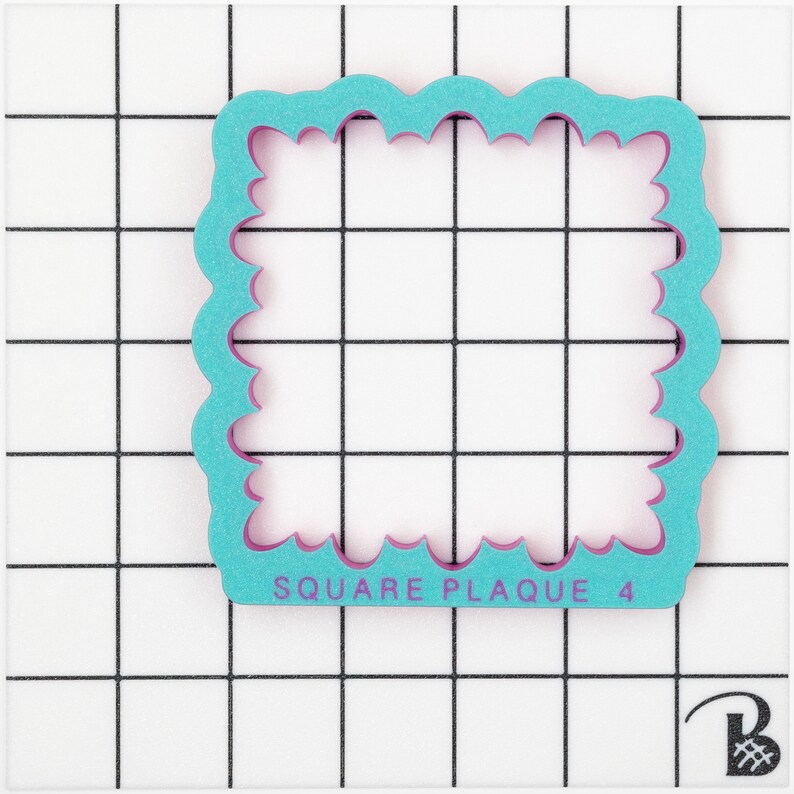 May include: A turquoise blue square cookie cutter with a scalloped edge and a pink inner edge. The cutter is labelled "SQUARE PLAQUE 4".