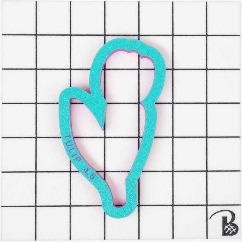 Op de afbeelding: Een turquoise blauwe en roze plastic koekjesvormer in de vorm van een tulp met de tekst "TULIP 4.5" aan de zijkant.