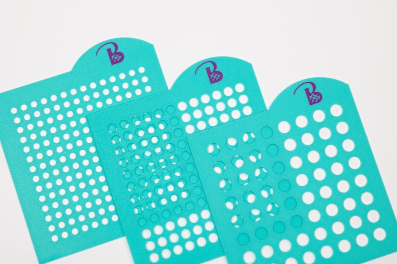 May include: Three turquoise blue stencils with different sized circles cut out. The stencils have a rounded top with a purple logo that says "Beads & Beyond".