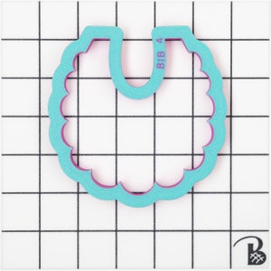 May include: A teal and purple bib-shaped cookie cutter with a scalloped edge. The text "BIB 4" is printed on the top right side of the cutter. The cutter is made of plastic and is set against a white grid background.