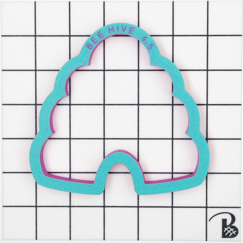 May include: A two-tone cookie cutter shaped like a beehive. The outer layer is a bright teal, and the inner layer is a deep magenta. The text "BEE HIVE 4.5" is printed in magenta on the top arch of the cutter.