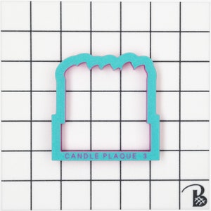 K&ouml;nnte beinhalten: Ein t&uuml;rkisblauer Ausstecher in Form einer Kerzenplatte mit dem Text "CANDLE PLAQUE 3" auf der Unterseite.