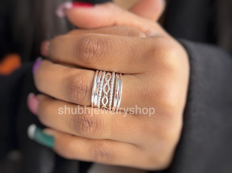 May include: A stackable silver ring set with various designs, including twisted rope and openwork patterns. The rings are worn on a finger, showcasing the different textures and styles. The shop name "shubhjewelryshop" is visible in the image.