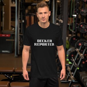 Puede incluir: Una camiseta negra con texto blanco que dice "DECKER REPORTED."