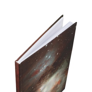 Op de afbeelding: Een gesloten hardcover-journaal met een donkerbruine omslag met een nevelprint. Het journaal is open om blanco witte pagina's te laten zien.