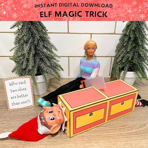 Può includere: Una scena a tema natalizio con una bambola, un elfo e una scatola per trucchi di magia. La scatola è gialla e rossa, con una sega e un cartello che dice: "Chi ha detto che due elfi sono meglio di uno?!" Il testo "ELF MAGIC TRICK" è in alto.