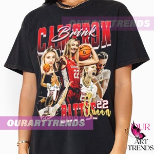 May include: Black t-shirt with a vintage-style graphic of a basketball player with the text "Cameron Brink" and "Battle Queen 22" printed on it.