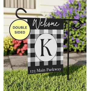 May include: Black and white buffalo plaid welcome garden flag with a white circle and the letter "K" in black. The flag also has the text "Welcome" and "123 Main Parkway".