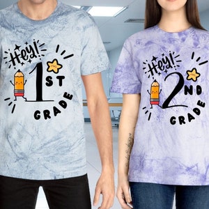 May include: Two tie-dye t-shirts with a cartoon pencil and the text "Hey! 1st Grade" and "Hey! 2nd Grade".