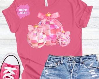 May include: Pink t-shirt with a design of three pink and white Christmas ornaments with bows.
