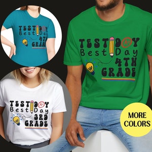 May include: Three t-shirts with a graphic design featuring a pencil, lightbulb, and the text "Test Day Best Day 4th Grade" or "Test Day Best Day 3rd Grade". The shirts are available in green, white, and blue.