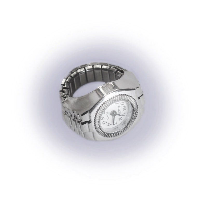 May include: A silver watch ring with a white face and black hands. The watch face has black numbers and the word "Japan" printed on it.