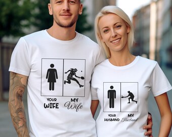 Op de afbeelding: Twee witte T-shirts met een zwart grafisch ontwerp. De grafiek toont een stickfiguur die tennis speelt met de tekst "Your Wife" en "My Wife".