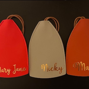 May include: Five leather keychains with gold lettering. The keychains are in the colors pink, red, gray, orange, and navy blue. The names on the keychains are Katie, Mary Jane, Nicky, Macy, and Taylor.