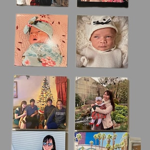 May include: A collage of eight photos featuring families and babies. The photos are arranged in a grid pattern. The top left photo shows a couple standing in front of the Brooklyn Bridge. The top right photo shows a family portrait with a cartoon style. The middle left photo shows a baby wrapped in a blanket. The middle right photo shows a baby wearing a white hat with cat ears. The bottom left photo shows a woman holding a baby. The bottom right photo shows a woman holding a baby in a pool. The photos are printed on square canvases.